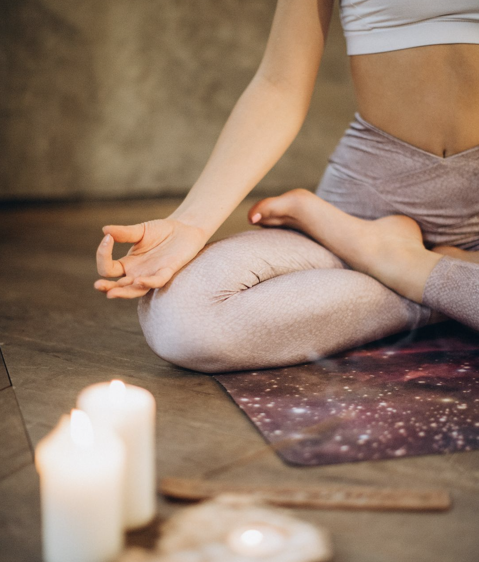 Close-up of a person seated in meditation with candles, preparing for a calming breathwork session focused on grounding and emotional release.