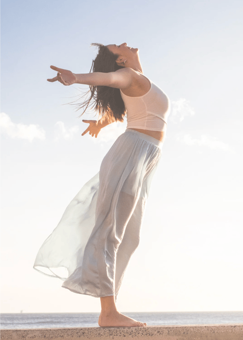 Woman Standing on beach with arms wide out depicting how your healing journey may unfold 