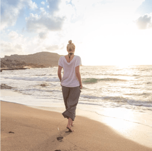 woman walking on a serene beach and self reflecting 